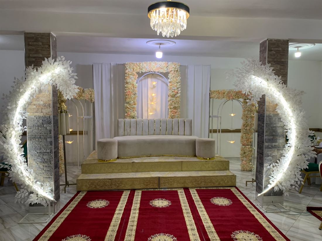 Scène des mariés décorée avec arches lumineuses — salle des fêtes Le Petit Jardin
